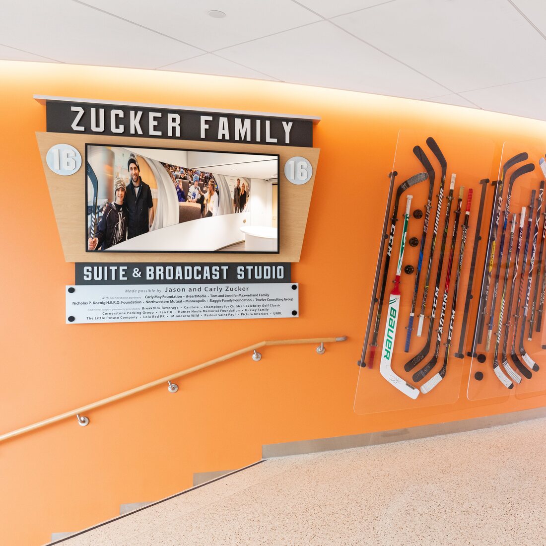 The Zucker Family Suite and Broadcast Studio wall display with hockey sticks and the GIVE16 story